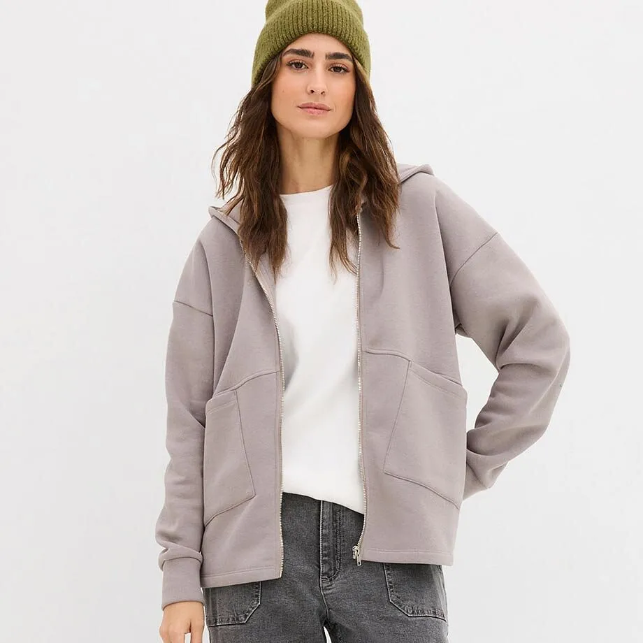 Maglia bianca e felpa grigia con zip sopra jeans grigi.