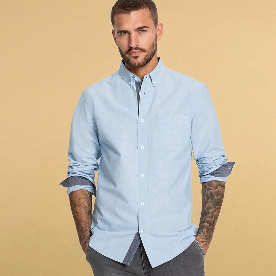 Camicia button-down azzurra con maniche arrotolate.