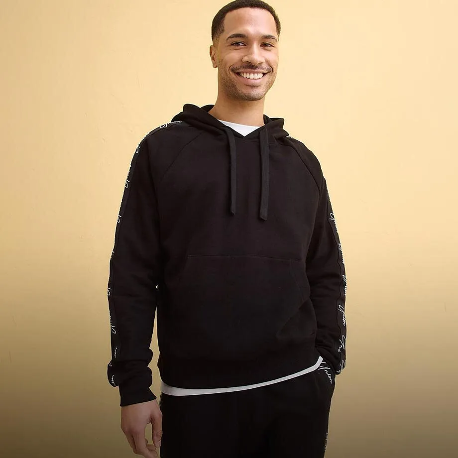 Felpa nera con cappuccio sopra una maglietta bianca e pantaloni comodi.