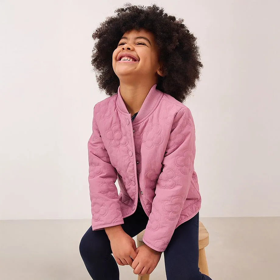 Una giacca rosa con bottoni sopra un top scuro.