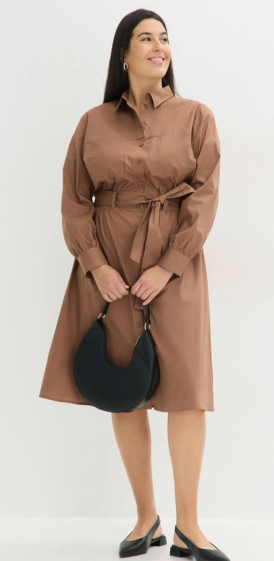 Abito chemisier marrone con cintura da annodare, abbinato a una borsa nera.
