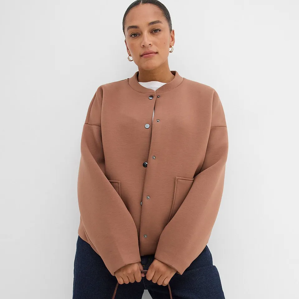 Giacca color terracotta con bottoni a pressione e scollo rotondo.