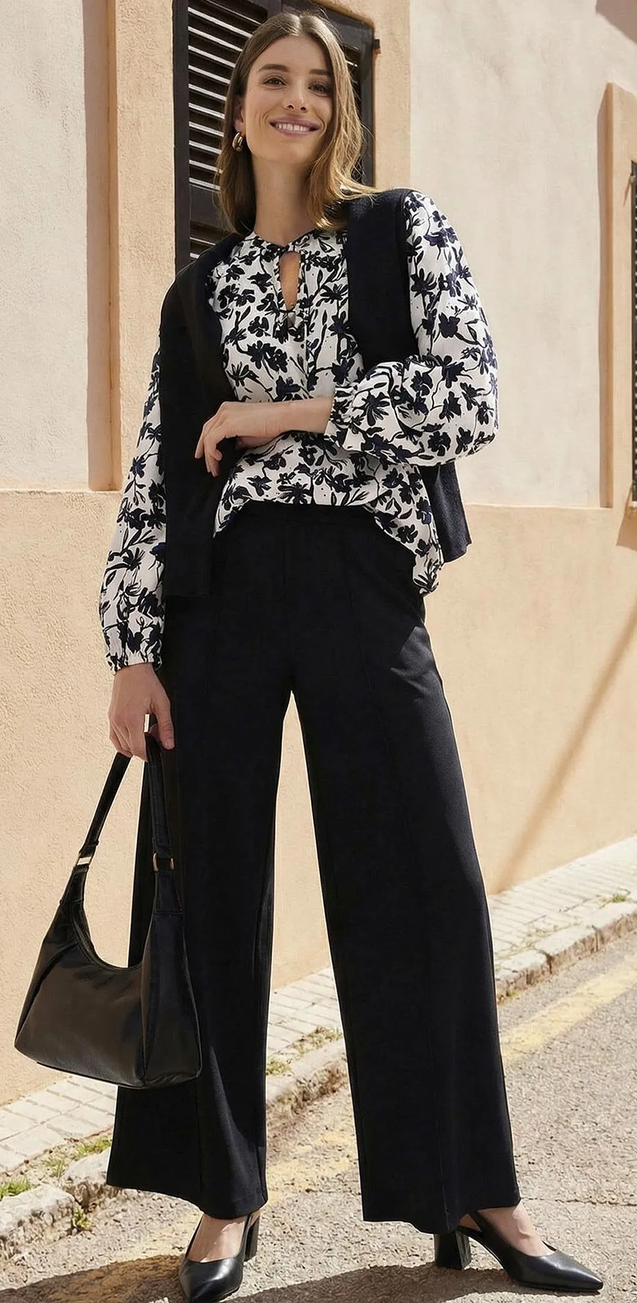 Pantaloni neri abbinati a una camicetta fantasia in bianco e nero.