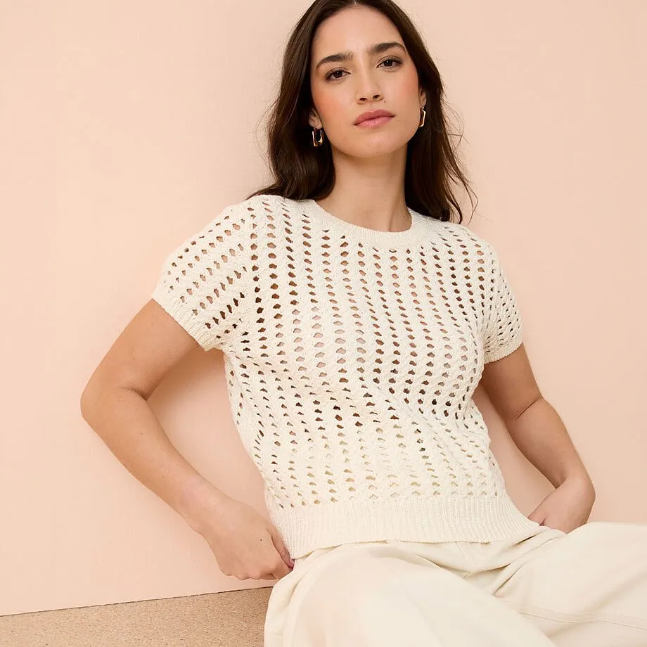 Maglia bianca traforata con maniche corte e scollo rotondo.