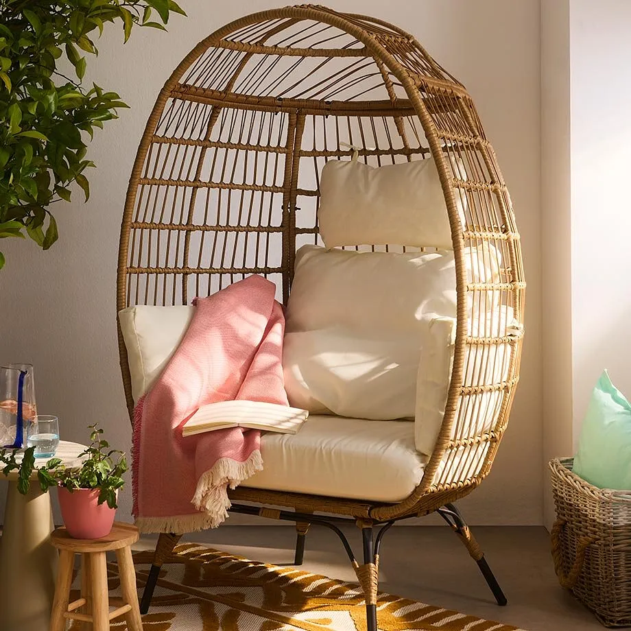 Poltrona in rattan con morbidi cuscini chiari.