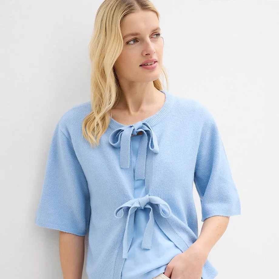 Maglia azzurra con fiocco sul collo.