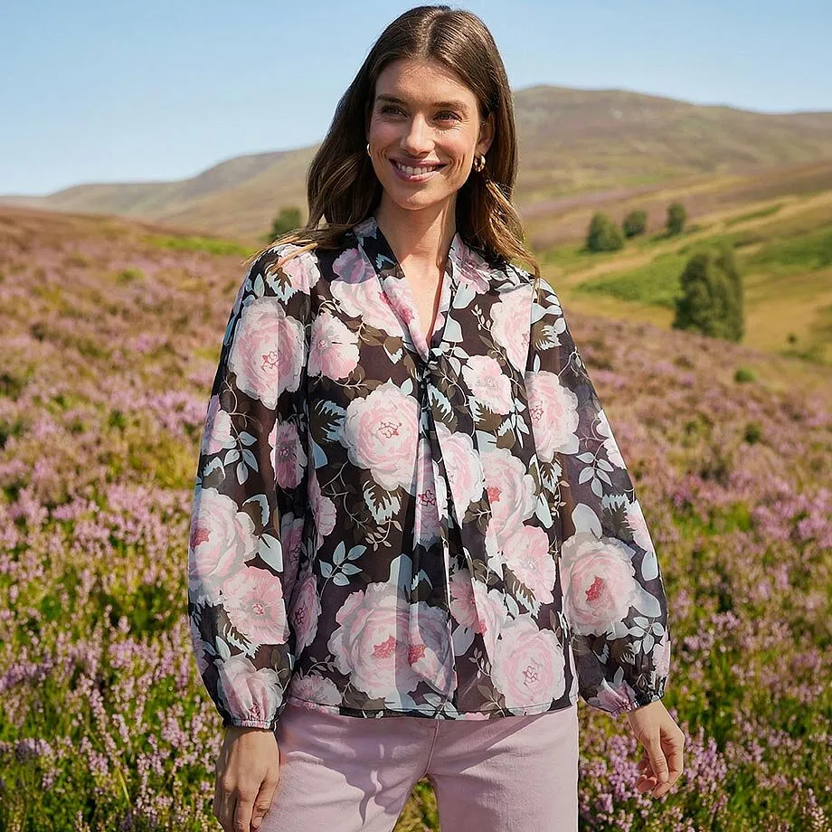 Una blusa a fiori con delicati boccioli rosa su fondo scuro.