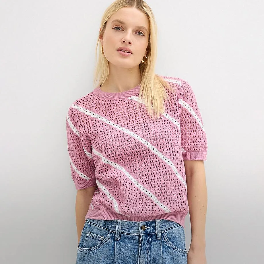 Maglione rosa traforato con strisce diagonali, abbinato a un classico paio di jeans.