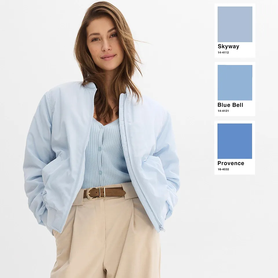 L'outfit &egrave; caratterizzato da tenui tonalit&agrave; pastello: un cardigan azzurro sopra un top delicato, abbinato a pantaloni beige.