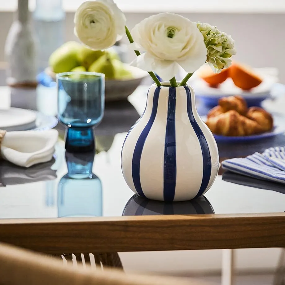 Un vaso a strisce con fiori bianchi.