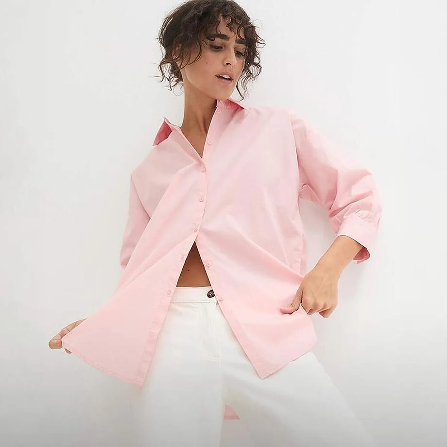 Camicetta rosa pallido a maniche lunghe abbinata a pantaloni bianchi.