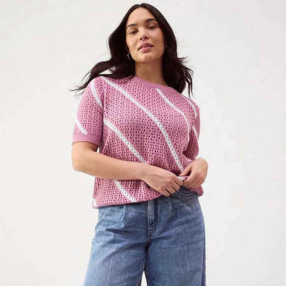 Maglione estivo lavorato a maglia morbido color rosa, abbinato a jeans dal taglio ampio.