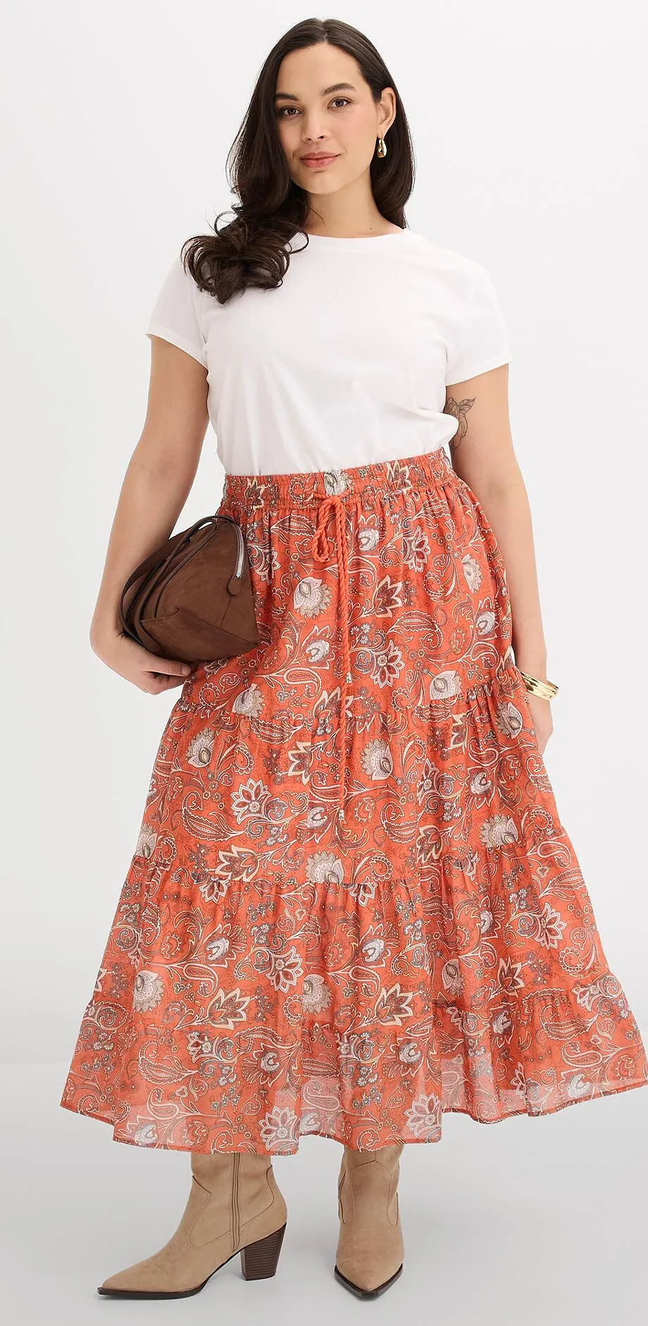 Maglietta bianca abbinata a una gonna lunga arancione in fantasia. 