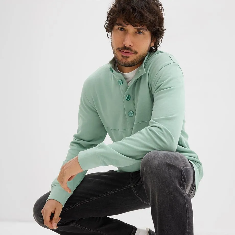 Felpa verde menta con abbottonatura, maglietta bianca sotto e jeans scuri.