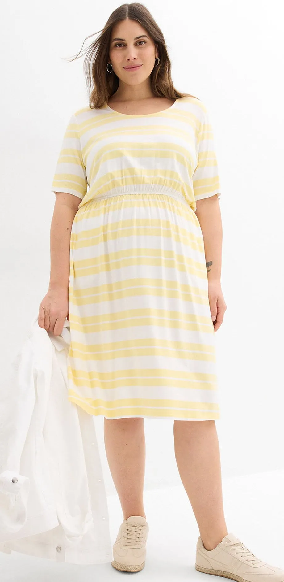 Abito a righe giallo chiaro e sneaker beige.