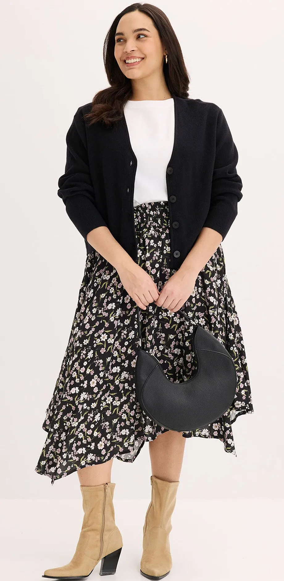 Cardigan nero, maglia bianca e gonna midi a fantasia bianca e nera.