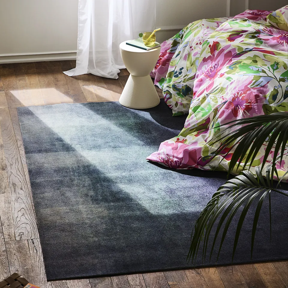 Il motivo floreale colorato su cuscini e copriletto impreziosisce l'accogliente soggiorno con un tappeto di grande stile.