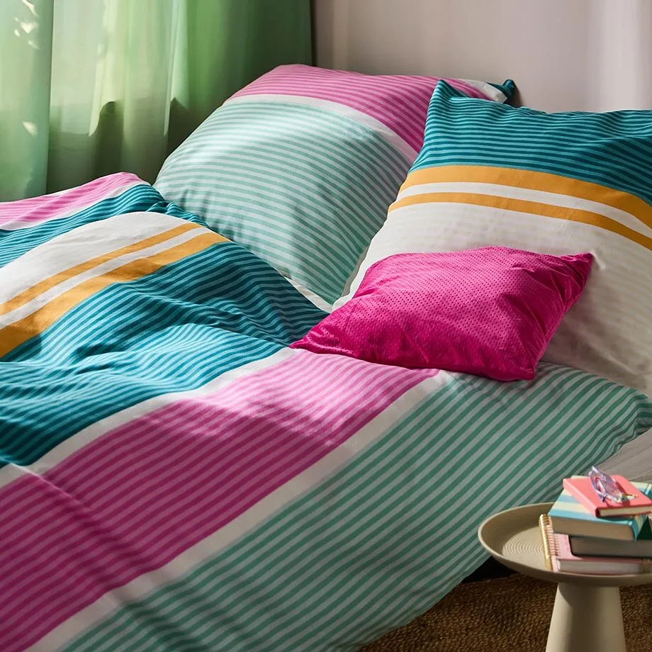 Lenzuola colorate a righe rosa, verdi e arancioni adornano l'accogliente letto.