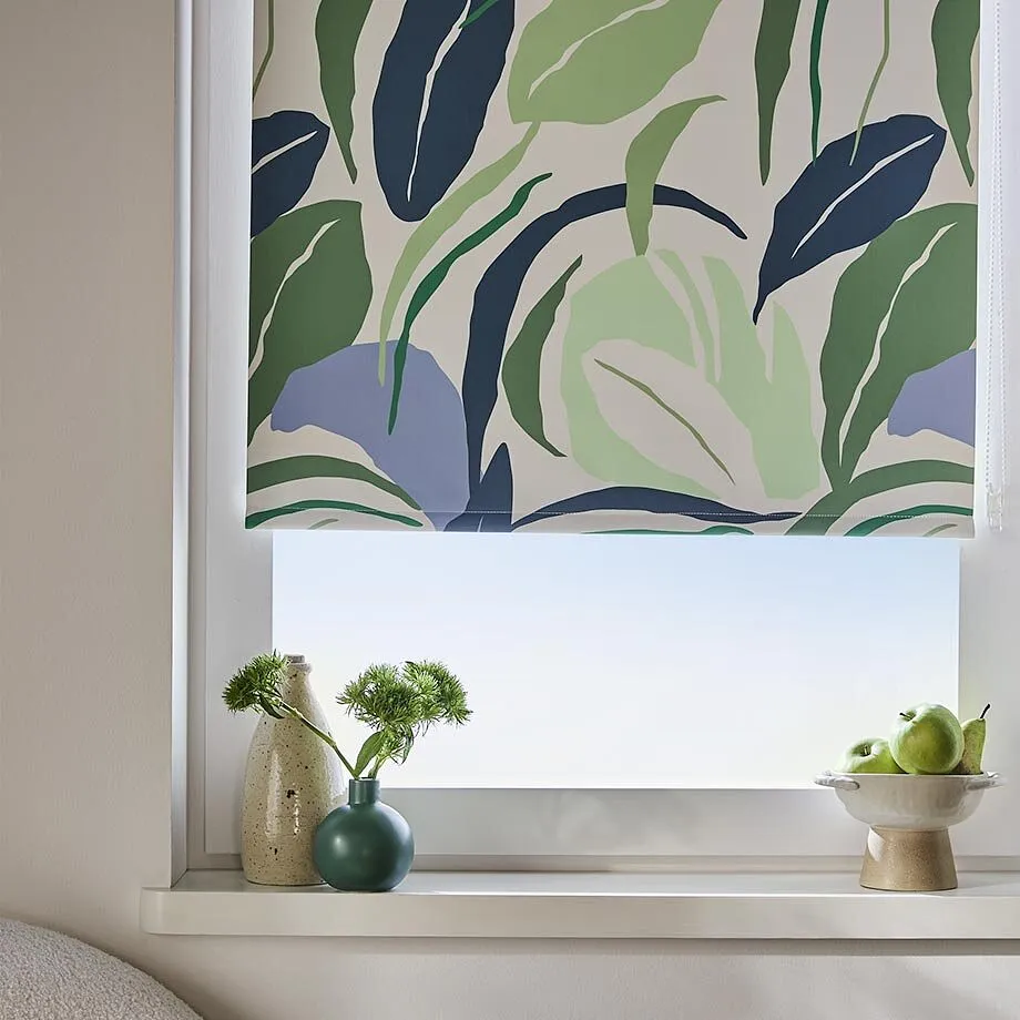 Un'elegante tenda a rullo con un motivo a foglie verde-blu impreziosisce la finestra luminosa del moderno soggiorno.