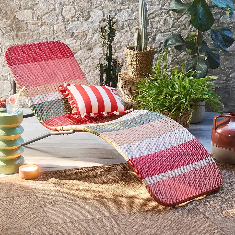 Cuscino a righe rosse e bianche su una sedia da giardino, perfetto per rilassanti giornate estive all'aperto.