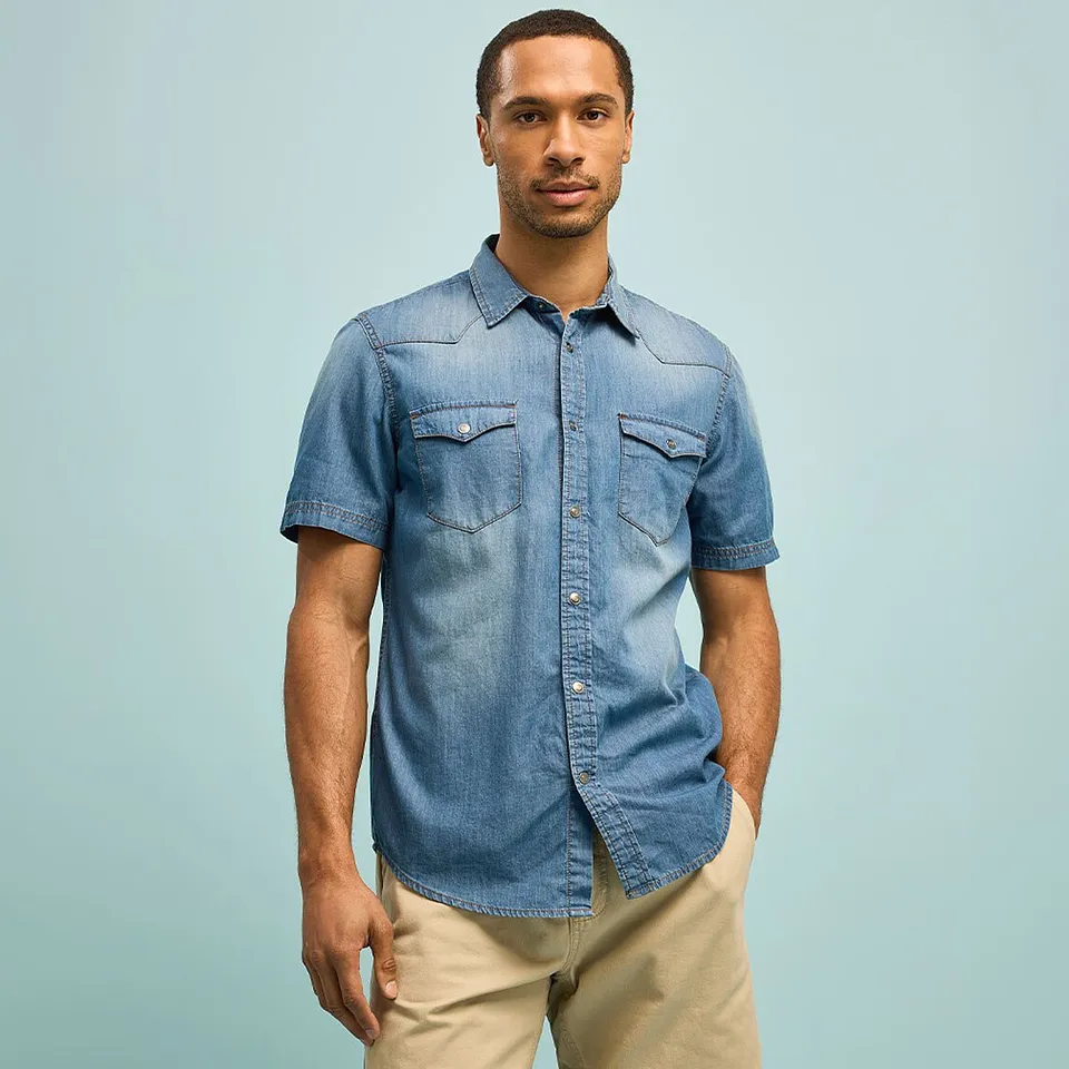 Camicia casual blu in denim a maniche corte e pantaloni beige.