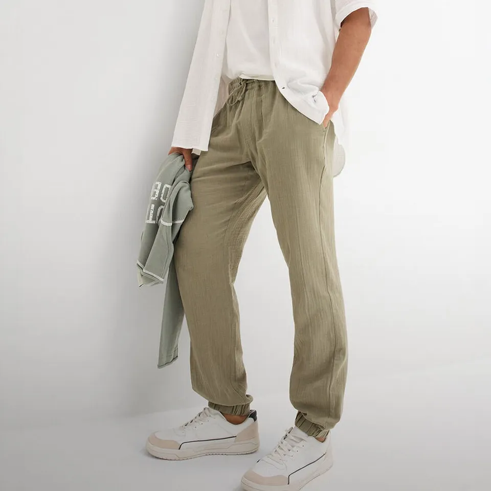 Pantaloni comodi verde oliva con t-shirt bianca e camicia bianca.