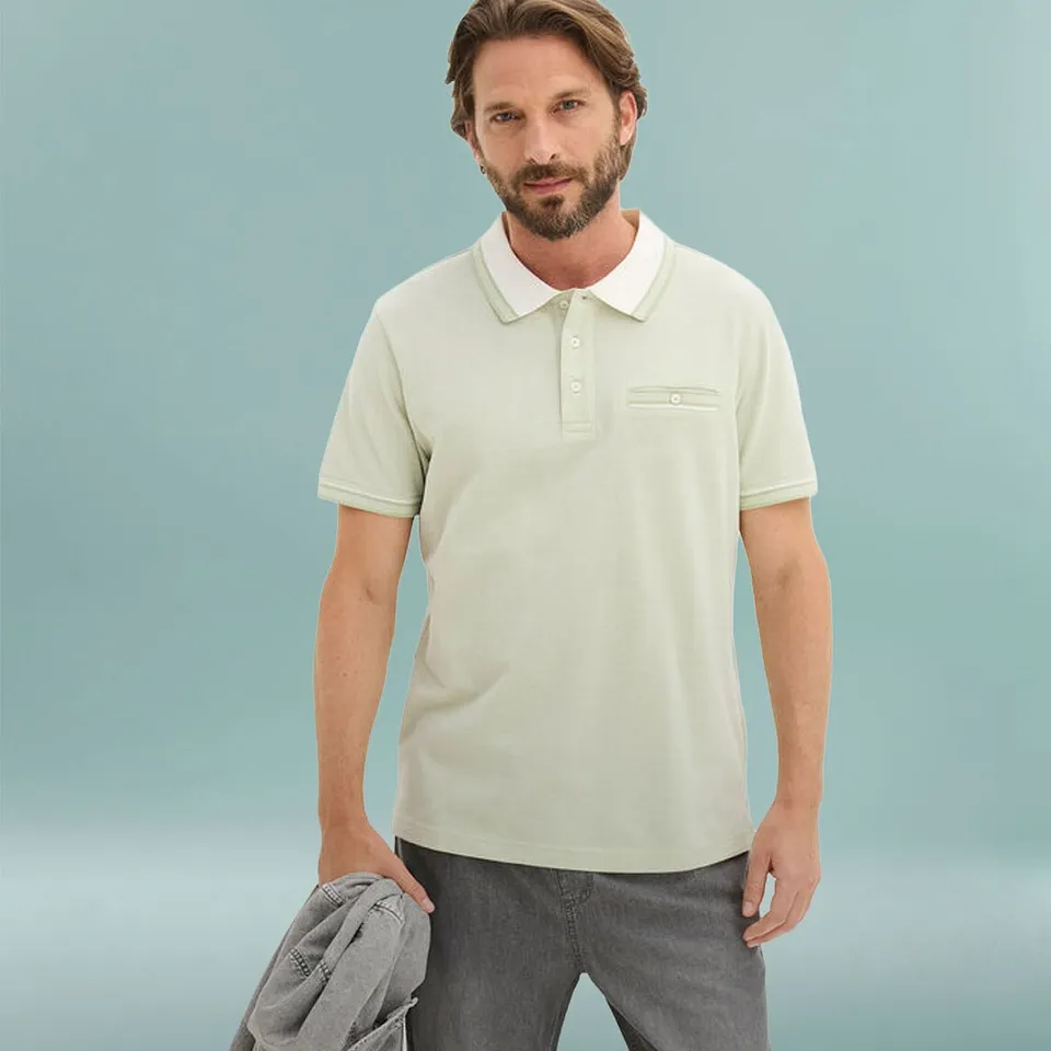 Polo verde chiaro con colletto bianco e pantaloni grigi.
