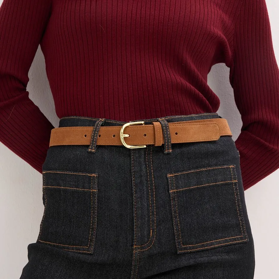 Maglione lavorato a maglia abbinato a jeans e cintura di pelle marrone.