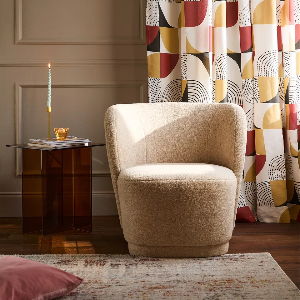 Una poltrona color beige e tende dai motivi geometrici colorati creano nell'ambiente un'atmosfera calda e moderna.