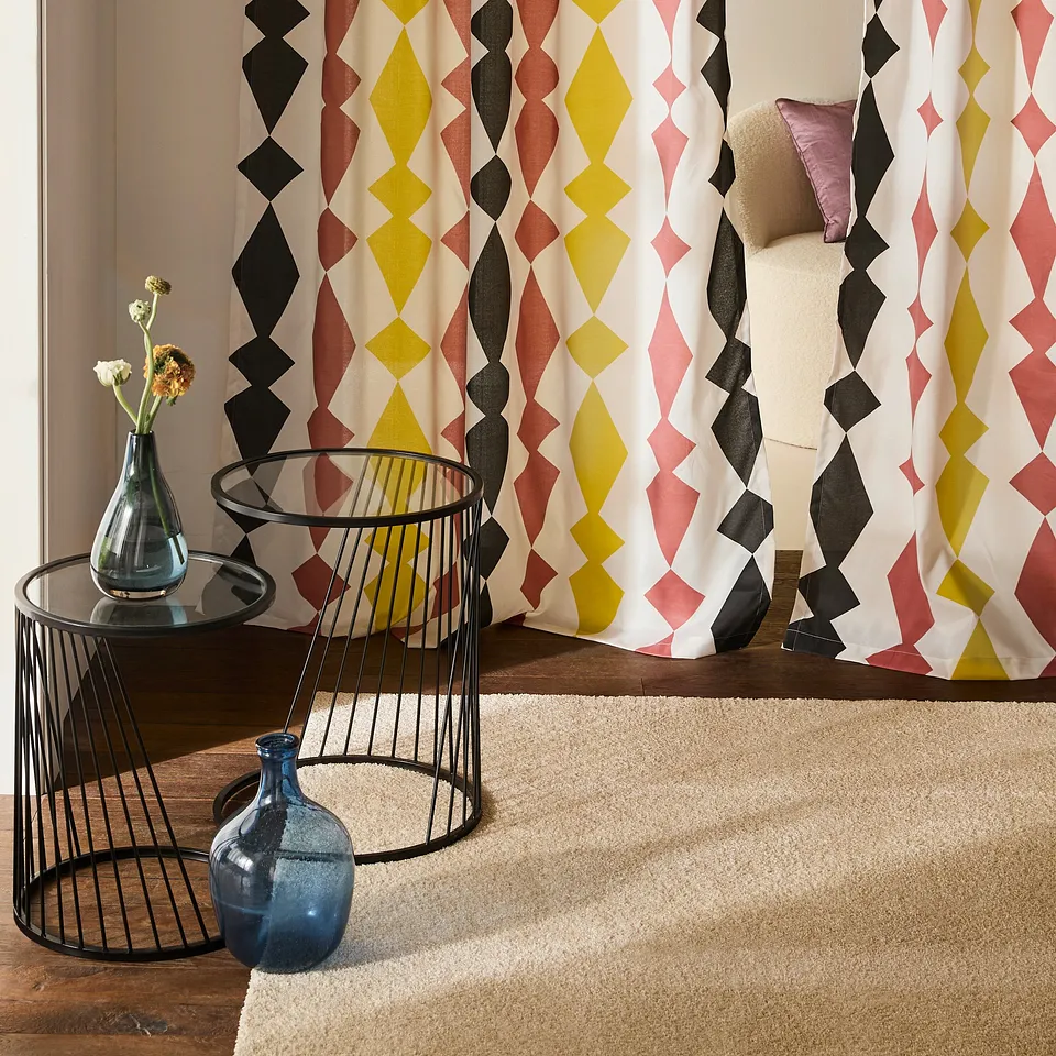 Il soggiorno &egrave; decorato da tende colorate con motivi geometrici a rombi nei toni del giallo, del rosa e del nero.