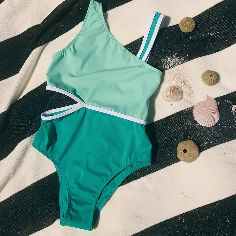 Costume da bagno da bambina color turchese con strisce bianche e dal taglio sportivo.