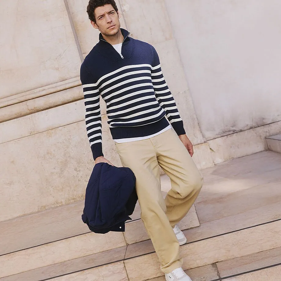 Maglione a righe blu navy e bianco, pantaloni beige e giacca blu scuro.
