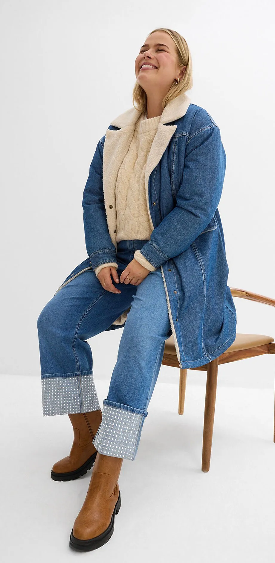 Look jeans con cappotto lungo, maglione beige e jeans.