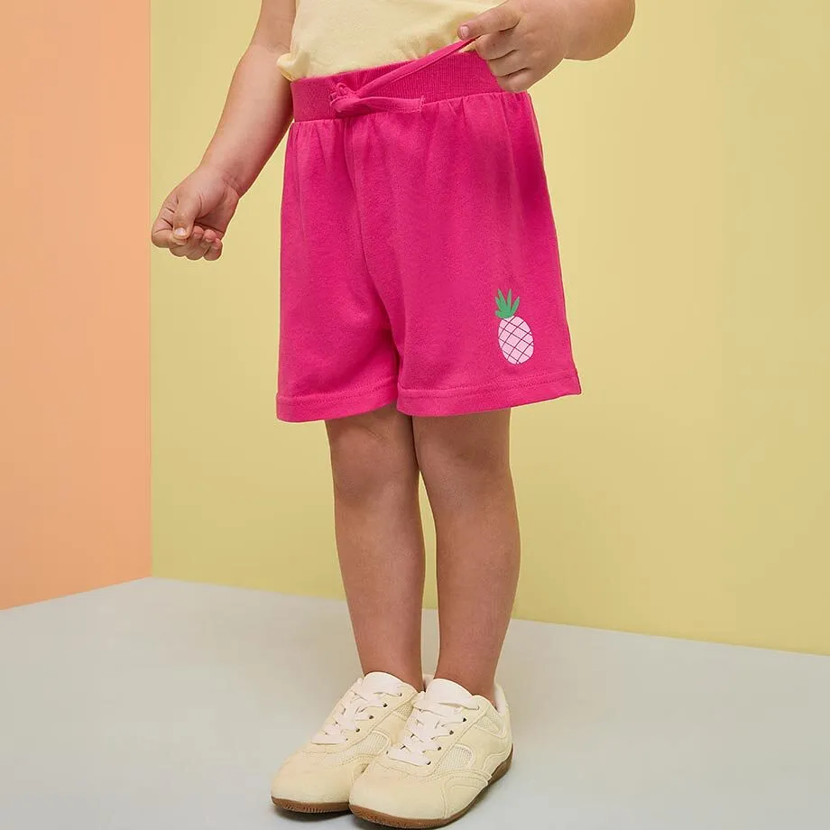 Pantaloncini rosa con motivo a forma di ananas e top chiaro.