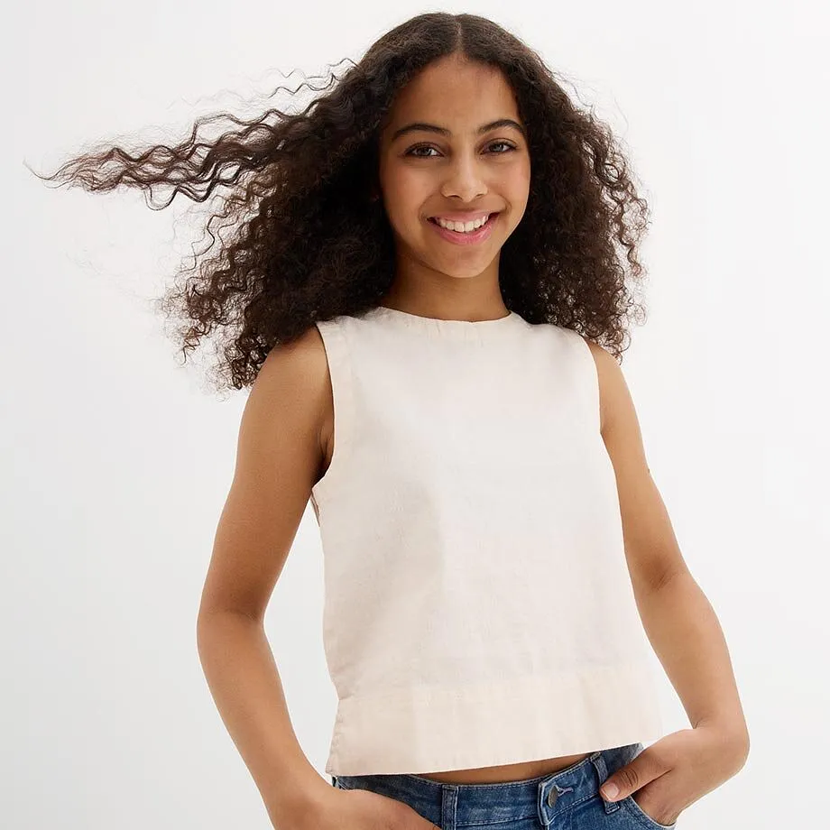 Top senza maniche color beige chiaro e jeans blu.