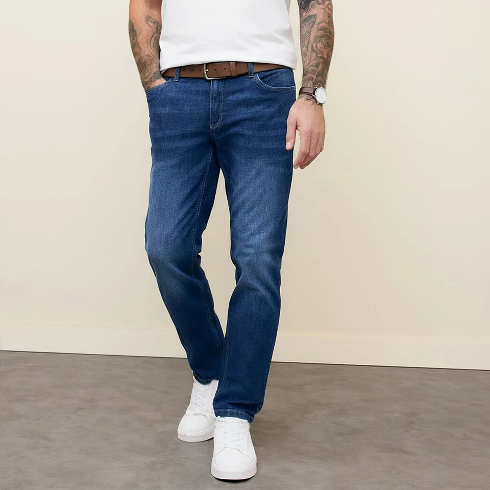 Look classico con maglietta bianca, jeans blu, cintura di pelle marrone e scarpe da ginnastica bianche.