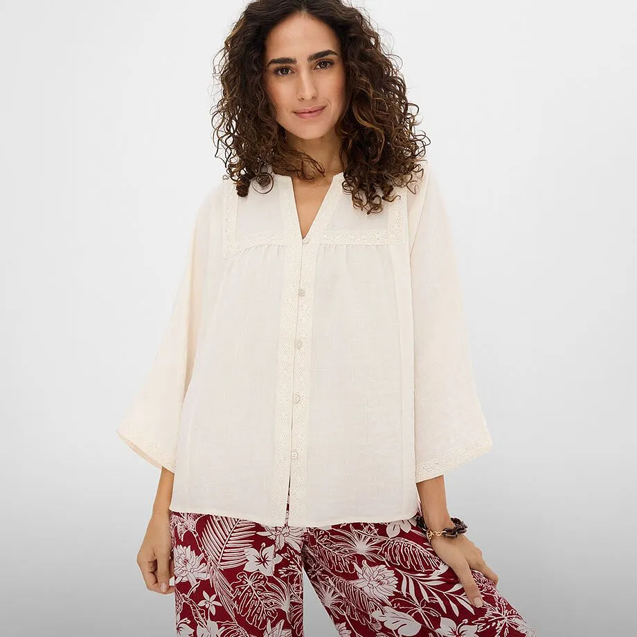 Elegante camicetta bianca abbinata a pantaloni a fantasia rosso e bianco.