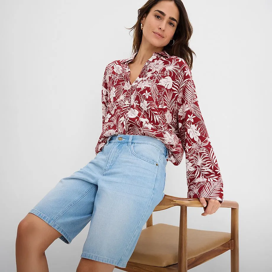Camicetta a fantasia rossa e bianca con scollo a V e shorts di jeans azzurri.