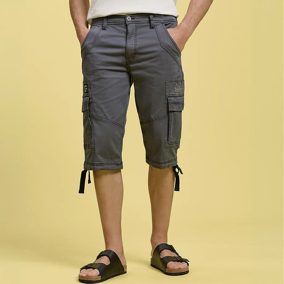 Pantaloncini cargo grigi con pratiche tasche laterali, maglietta bianca e sandali neri.