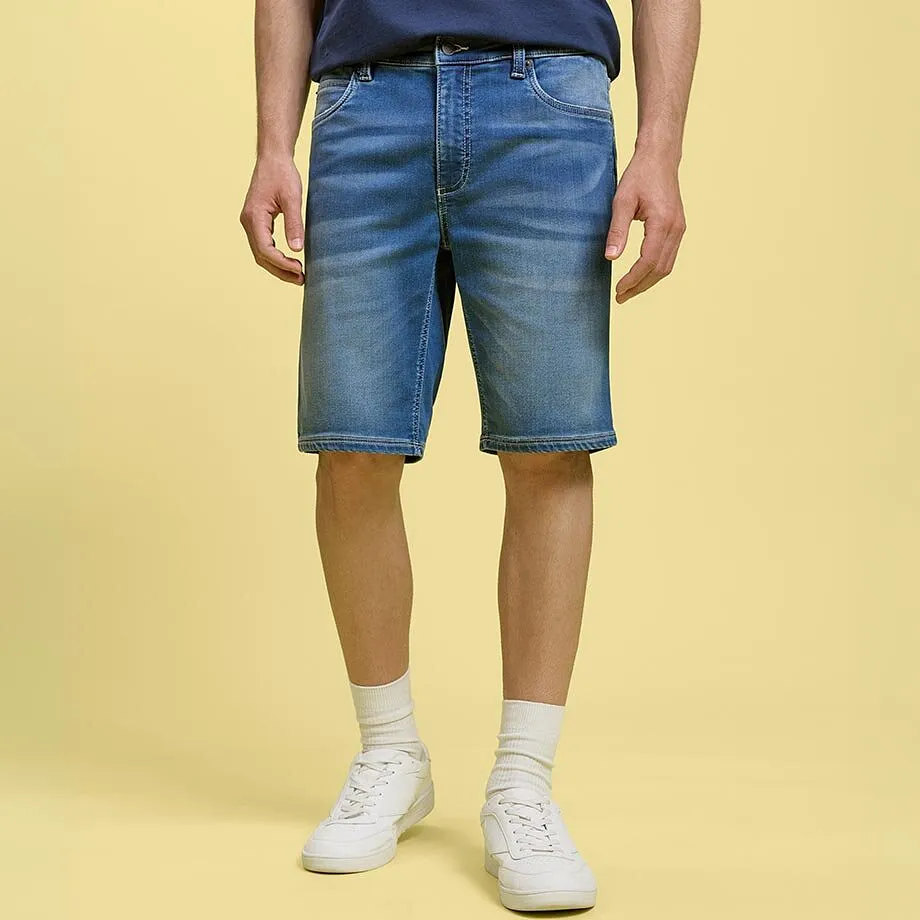 Bermuda di jeans casual e maglietta blu abbinati a scarpe da ginnastica bianche e calzini.