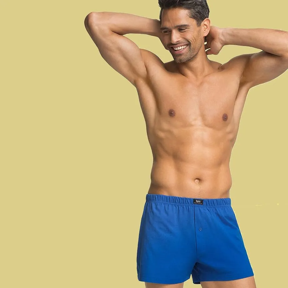 Un uomo muscoloso indossa dei boxer blu.