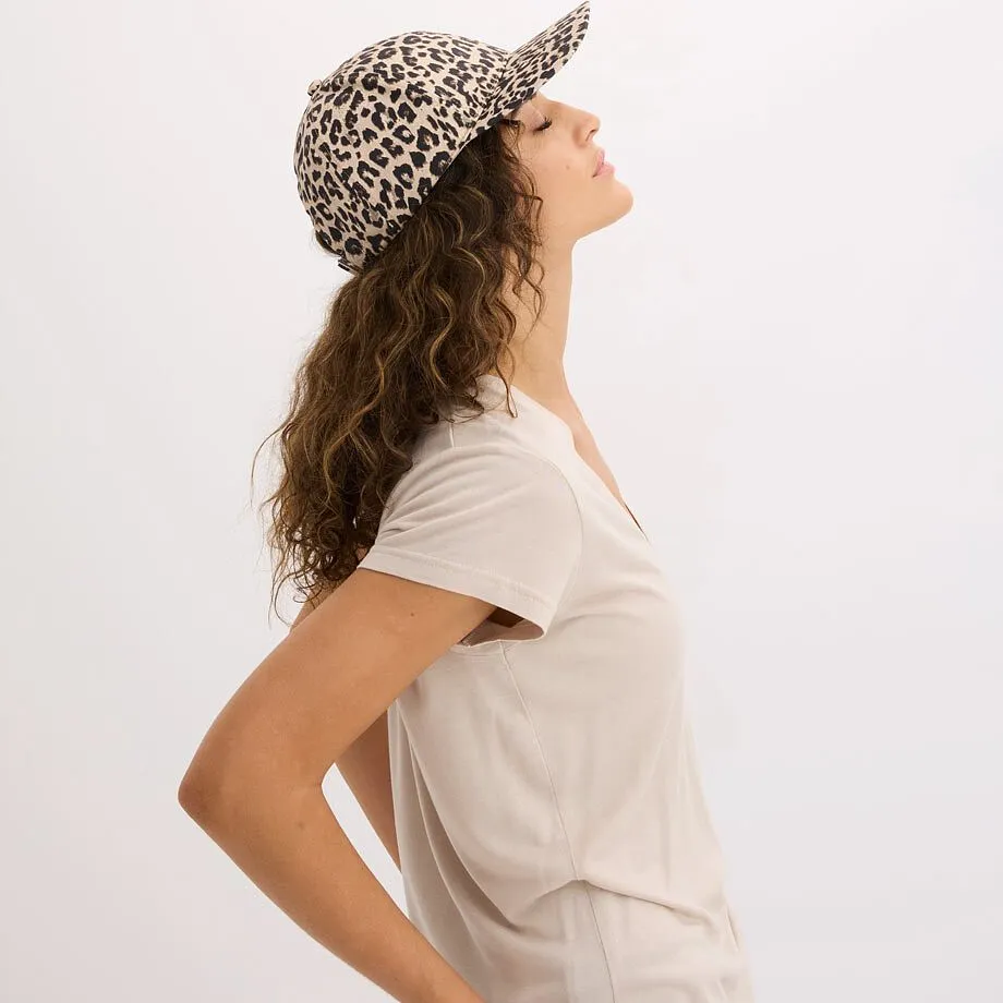 Cappellino alla moda con fantasia leopardata e maglietta beige.