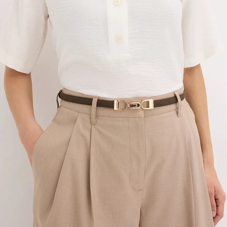 Camicetta bianca, cintura sottile con fibbia dorata e pantaloni beige.