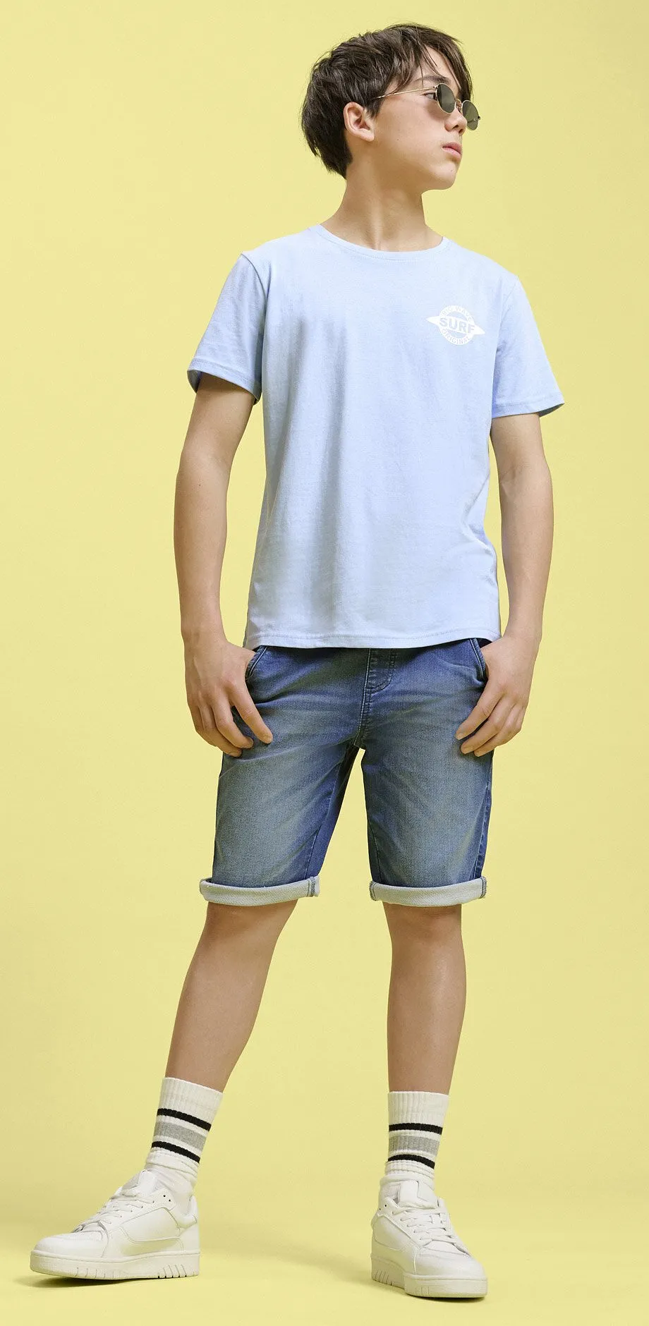 Maglietta azzurra e pantaloncini di jeans.