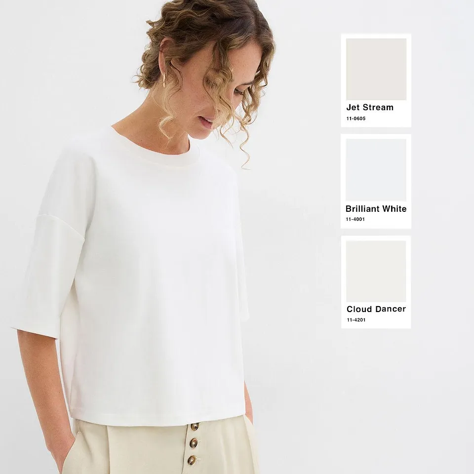Una blusa bianca alla moda e dal taglio morbido, abbinata a pantaloni chiari nei toni del crema.