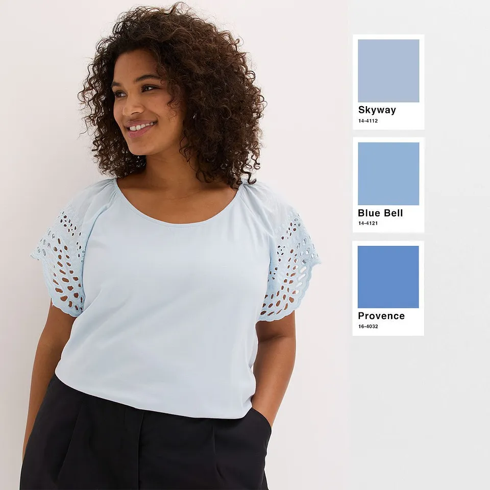 Maglietta fresca color azzurro con maniche traforate, abbinata a pantaloni semplici di colore scuro.