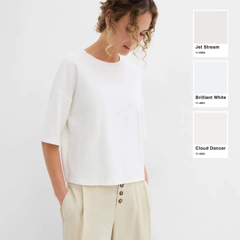 Una blusa bianca alla moda e dal taglio morbido, abbinata a pantaloni chiari nei toni del crema.
