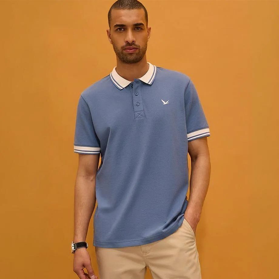 Polo blu con un elegante colletto bianco e pantaloni beige abbinati.