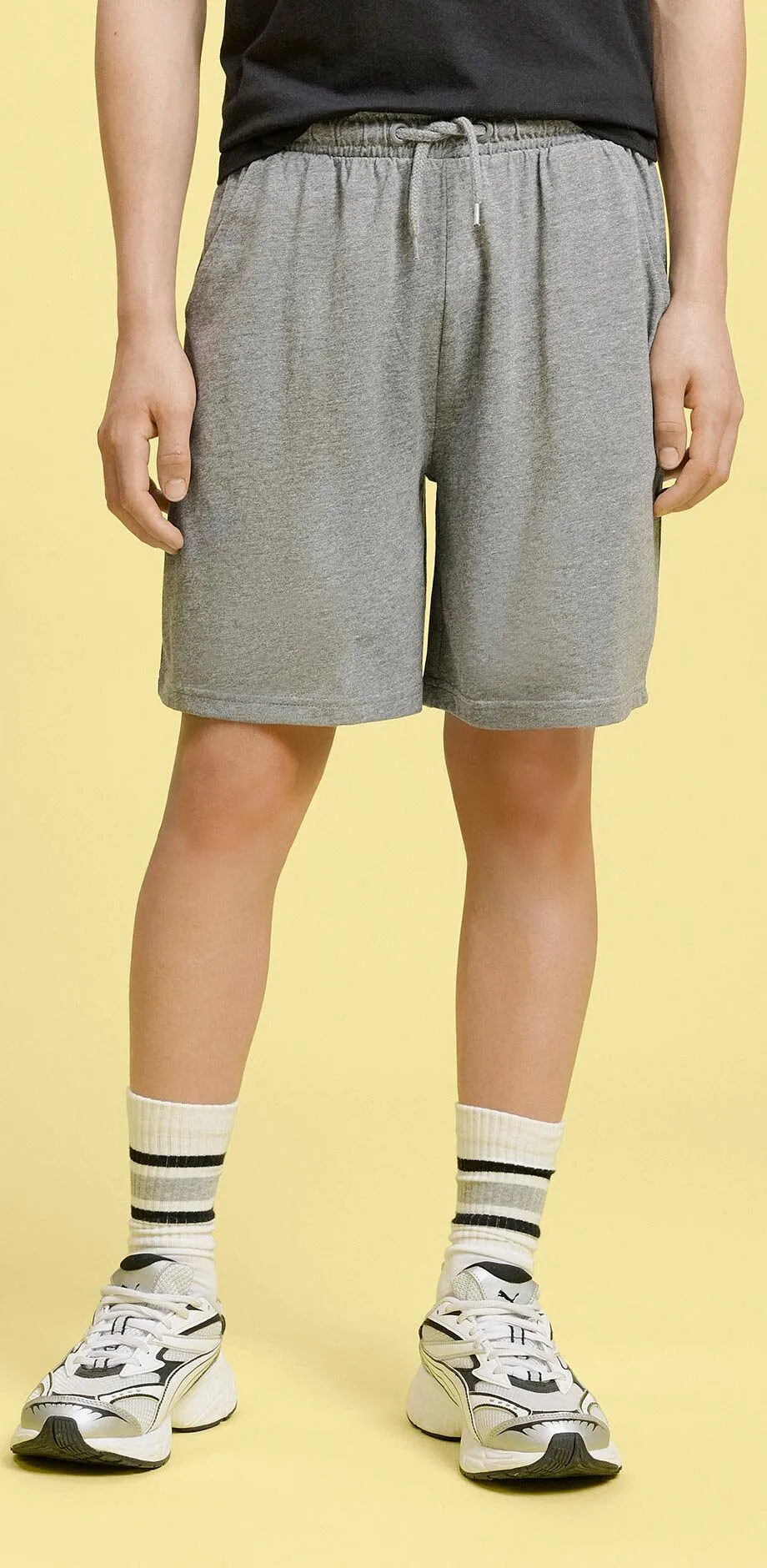 Outfit con maglietta nera e pantaloncini grigi.
