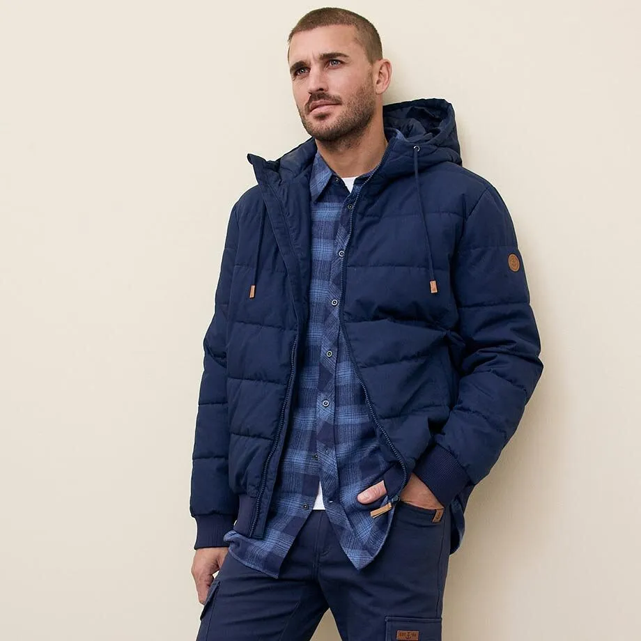 Giacca invernale blu scuro con cappuccio sopra una camicia a quadri.